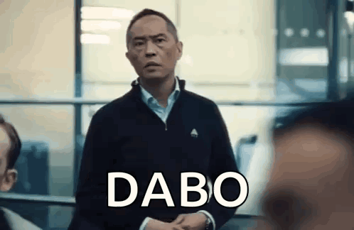 a man in a black jacket is standing in front of a window with the word dabo written on his face .