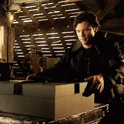 A Man In A Black Jacket Is Standing Next To A Large Box GIF