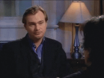 A Man In A Black Jacket Is Talking To Another Man GIF