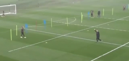 A Man In A Black Jacket Is Walking On A Soccer Field With Another Man GIF