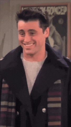 A Man In A Black Jacket Smiles In Front Of A Poster That Says Lucky Forced GIF
