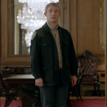 A Man In A Black Jacket Stands In A Room GIF