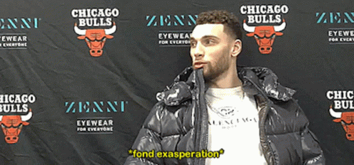 A Man In A Black Jacket Stands In Front Of A Chicago Bulls Backdrop GIF
