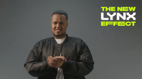 A Man In A Black Jacket Stands In Front Of A Lynx Effect Ad GIF