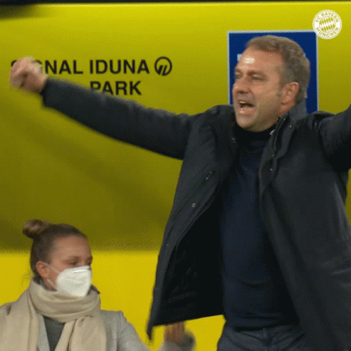 A Man In A Black Jacket Stands In Front Of A Sign That Says National Iduna Park GIF