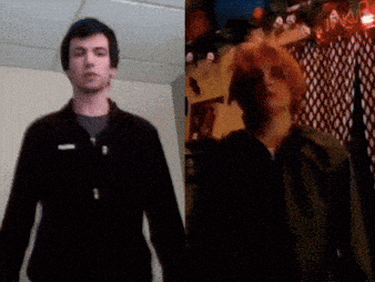 A Man In A Black Jacket Stands Next To Another Man GIF