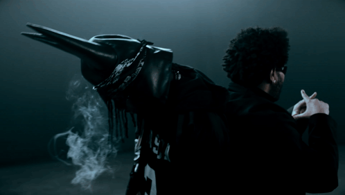 A Man In A Black Jacket With The Letter P On The Back Is Smoking A Cigarette GIF