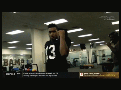 A Man In A Black Jersey With The Number 13 On It Stands In A Gym GIF