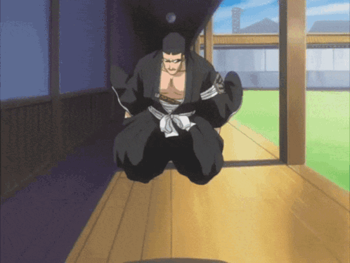 A Man In A Black Kimono Is Kneeling Down On A Wooden Floor GIF