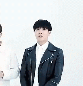 A Man In A Black Leather Jacket And White Shirt Is Standing Next To Another Man In A White Shirt . GIF
