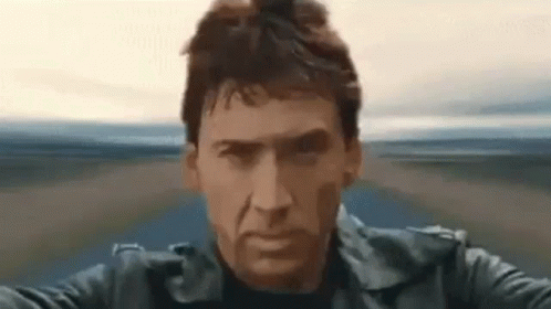 A Man In A Black Leather Jacket Is Riding A Motorcycle On A Road . GIF