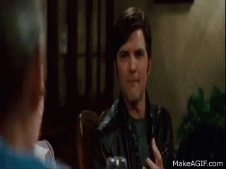 A Man In A Black Leather Jacket Is Sitting At A Table With A Glass Of Wine . GIF
