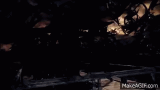 A Man In A Black Robe Is Standing In Front Of A Group Of Monsters In A Dark Room . GIF