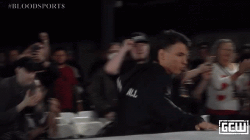 A Man In A Black Robe Stands In Front Of A Crowd With The Word Bloodsports On The Bottom Right GIF