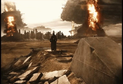 A Man In A Black Robe Stands On A Rock In Front Of A Burning City GIF