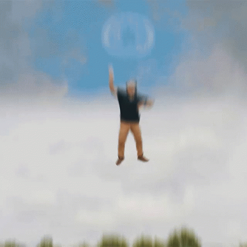 A Man In A Black Shirt And Brown Pants Is Jumping In The Air GIF