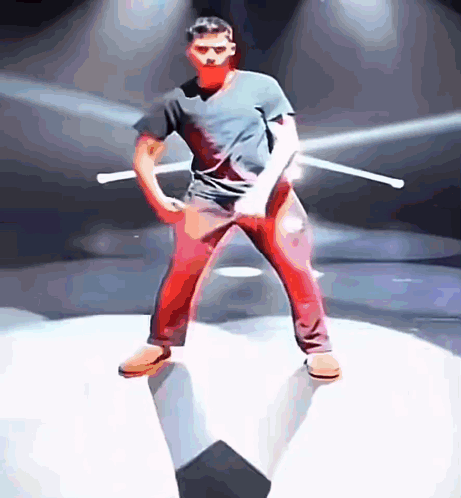 A Man In A Black Shirt And Red Pants Is Holding Two Sticks GIF