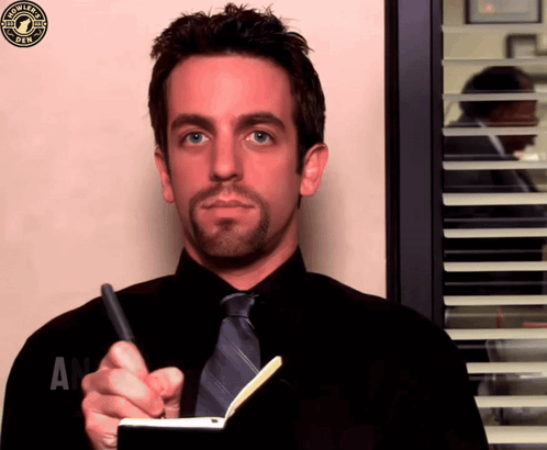 A Man In A Black Shirt And Tie Is Writing In A Notebook With A Starbucks Logo In The Corner GIF