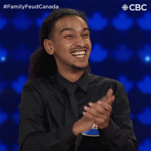 A Man In A Black Shirt And Tie With A Name Tag That Says Raheem GIF