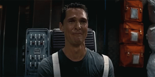 a man in a black shirt and white suspenders is crying in a room