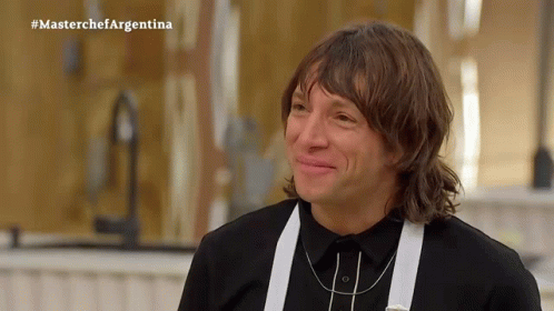 a man in a black shirt and white suspenders is smiling in front of a masterchef argentina sign