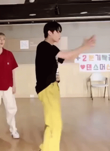 A Man In A Black Shirt And Yellow Pants Is Dancing In A Room GIF