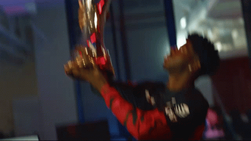 A Man In A Black Shirt Holds A Trophy In His Hand GIF