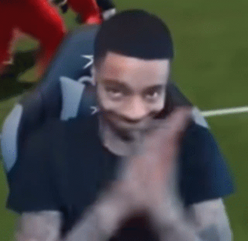 A Man In A Black Shirt Is Clapping His Hands While Sitting On A Couch . GIF