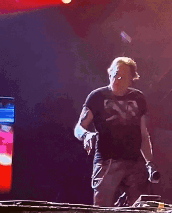 A Man In A Black Shirt Is Dancing In Front Of A Red Light GIF
