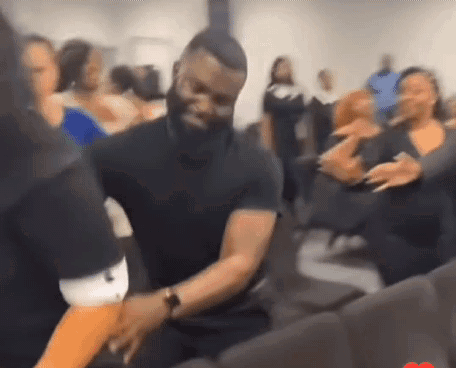 A Man In A Black Shirt Is Dancing With A Woman In A Crowd . GIF