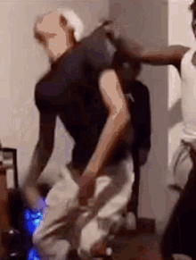 A Man In A Black Shirt Is Dancing With Another Man In A White Shirt In A Room . GIF