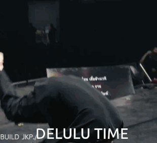 A Man In A Black Shirt Is Doing A Handstand With The Words Build Jkp Delulu Time Behind Him GIF