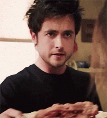 A Man In A Black Shirt Is Eating Pizza GIF