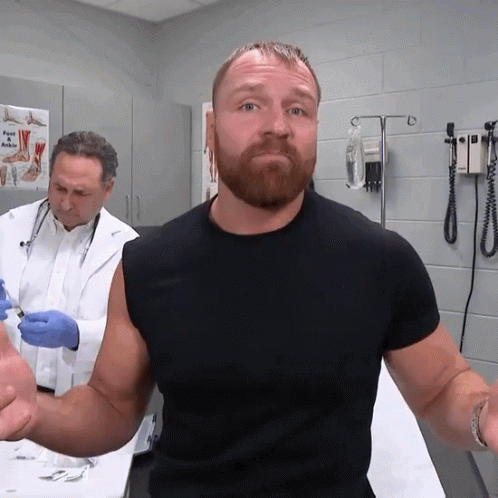 A Man In A Black Shirt Is Getting An Injection From A Doctor In A Hospital Room GIF