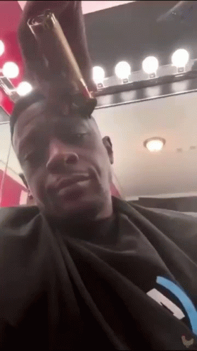 A Man In A Black Shirt Is Getting His Hair Cut GIF
