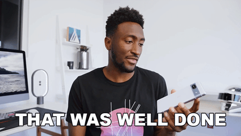 A Man In A Black Shirt Is Holding A Cell Phone And Says " That Was Well Done " GIF