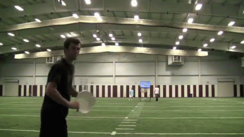A Man In A Black Shirt Is Holding A Frisbee GIF