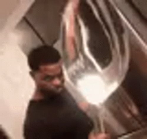 A Man In A Black Shirt Is Holding A Large Balloon In His Hand . GIF