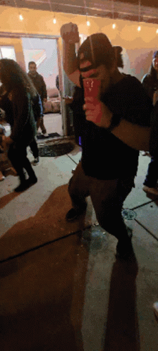 A Man In A Black Shirt Is Holding A Red Cup With The Letter T On It GIF