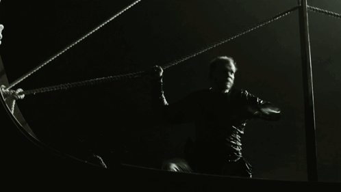 A Man In A Black Shirt Is Holding A Rope GIF