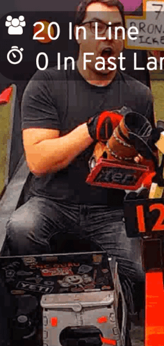A Man In A Black Shirt Is Holding A Tool And A Sign That Says ' 20 In Line 0 In Fast Lane ' GIF