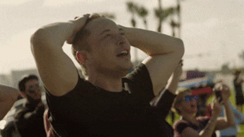 A Man In A Black Shirt Is Holding His Head In His Hands GIF