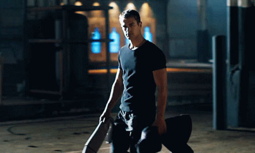 A Man In A Black Shirt Is Kneeling Down Holding A Skateboard GIF