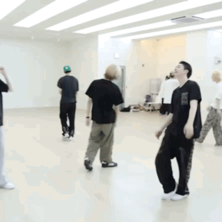 A Man In A Black Shirt Is Kneeling On The Floor In A Dance Studio GIF