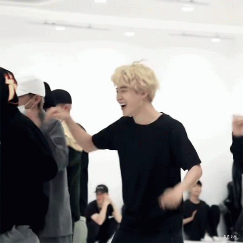 A Man In A Black Shirt Is Laughing While Dancing In A Room With Other People . GIF