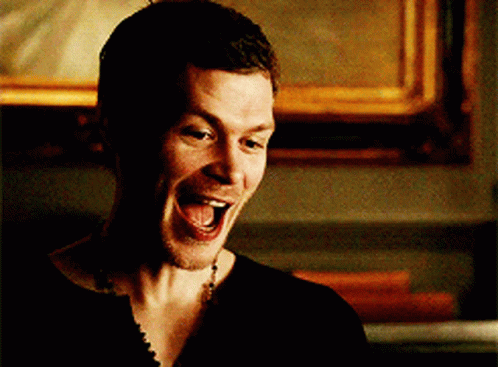A Man In A Black Shirt Is Laughing With His Mouth Wide Open GIF