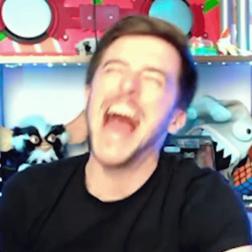 a man in a black shirt is laughing with his mouth wide open .