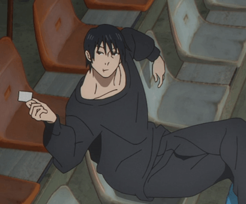 A Man In A Black Shirt Is Laying On A Chair Holding A Card GIF