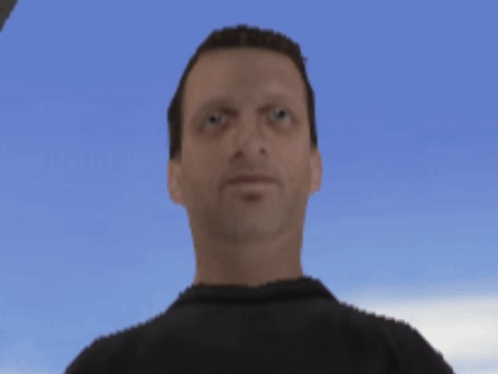 A Man In A Black Shirt Is Looking At The Camera With A Blue Sky In The Background GIF
