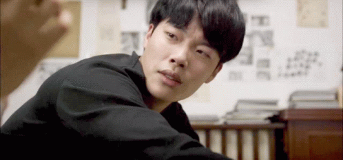 A Man In A Black Shirt Is Looking At The Camera With A Serious Look On His Face GIF
